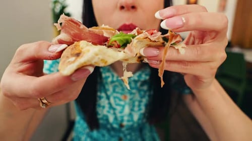 Woman Eating Pizza with Prosciutto and Greens