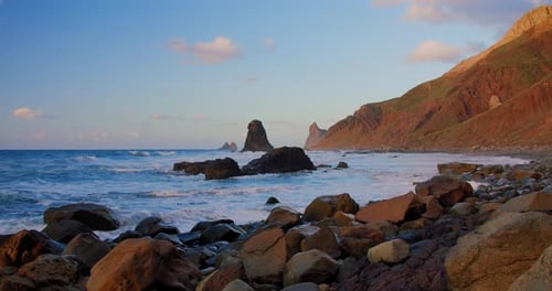 Beautiful natural sea landscape with rocky volcanic beach. Rolling big ocean waves to the stone shor