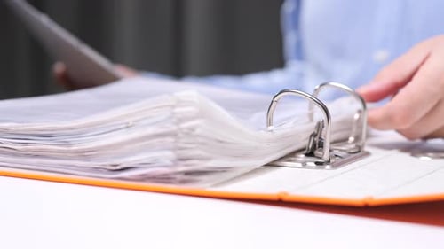 Office Worker Inserting Documents Into Folder Binder