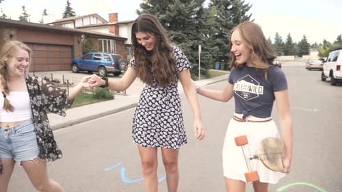 Teenage girl friends skateboarding together on a sunny summer neighborhood street