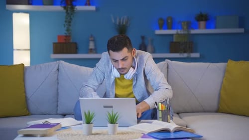 Man focusing on computer has serious expression. At home at night.