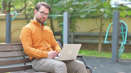 Thumbs Down by Man in Glasses Using Laptop Outdoor on Bench