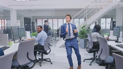 Un
jeune et beau chef d'entreprise joyeux vêtu d'un costume et d'une cravate danse au bureau. Diverse et M