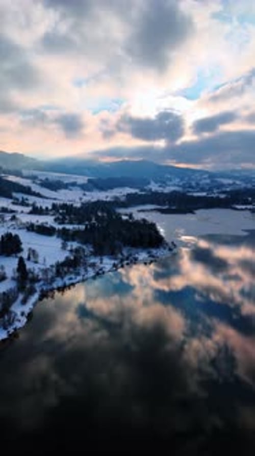 Rocks surrounding the lake are partially covered with snow.