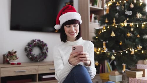 Woman Wearing Santa Hat Using Phone at Christmas