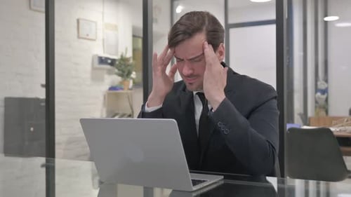 Middle Aged Businessman with Migraine in Office