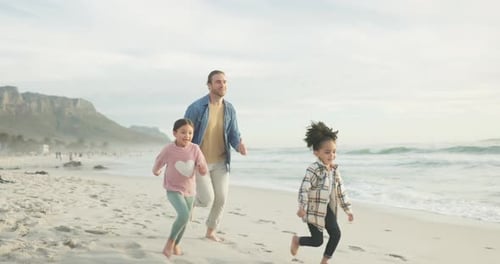 Family, father and children running on a beach together on holiday or vacation for bonding fun