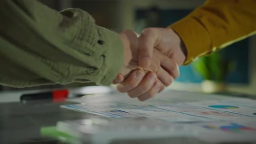 Business Handshake over Financial Documents in Office