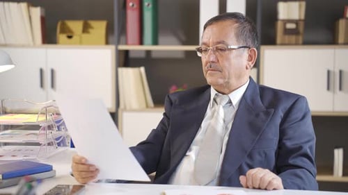 Successful Businessman Reviewing Positive Financial Documents at Office