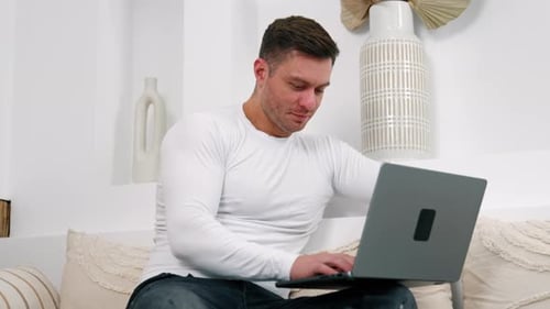 Man Using Laptop Computer at Home on Sofa