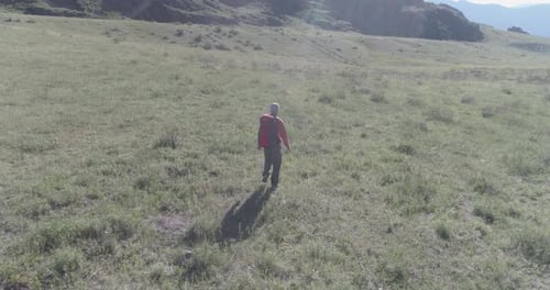 Flight Over Backpack Hiking Tourist Walking Across Green Mountain Field Huge Rural Valley at Summer