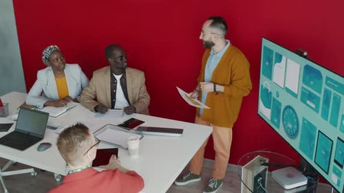 Male Brand Manager Discussing Draft of Promotional Stationery with Team