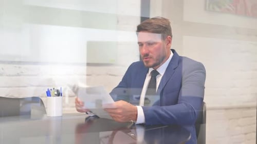 Man Reads Documents at Office Desk in Suit