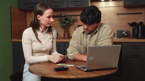 Financial Stress a Young Couple is Sitting at the Kitchen Table Experiencing Stress and