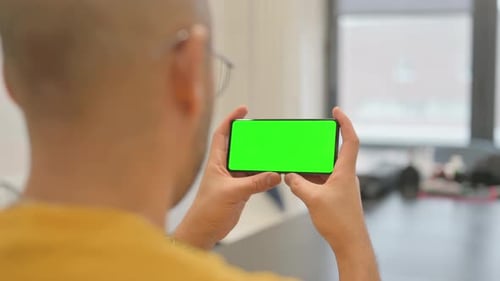 Hispanic Man Holding Phone Horizontal with Green Screen
