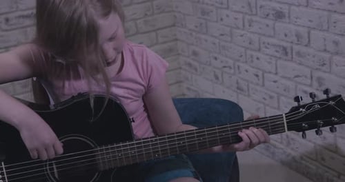 Child Plays Acoustic Guitar at Home