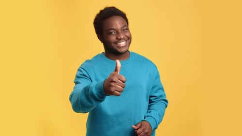 Smiling Man Giving Thumbs Up on Yellow Background