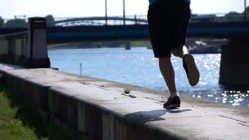 Young man jogging in the city riverside super slow motion training