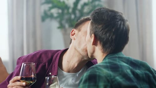 Loving Couple Clink Glasses and Kiss Indoors