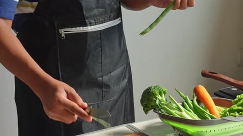 Man Hands Holding Knife While Slicing Green Beans At Kitchen. Preparation For Cooking Chicken Steak.