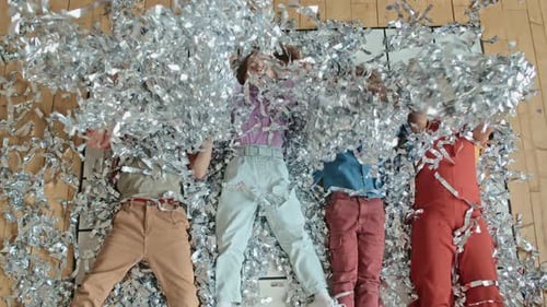 Cheerful Diverse Kids Lying on Floor and Playing with Tinsel at Party