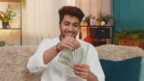 Indian Young Man Carefully Counting Cash Dollars Thoughtfully Planning Expenses Managing Money