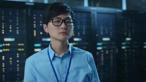 In the Modern Data Center: IT Engineer Working with Server Racks, Uses Laptop for Maintenance and D