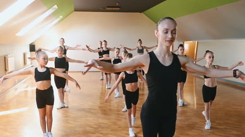 Many of the female kids practicing athletic exercises together indoors.