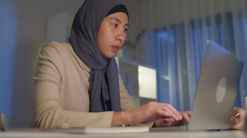 Woman working on laptop computer at night
