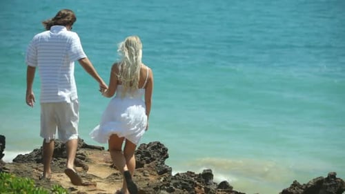 Couple Stand On Rocks Overlooking Ocean