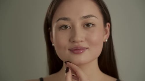Studio Shot of a Young Brunette Woman Standing Against a Gray Background A Beautiful Asian Woman