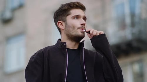 Bel homme vapotant l'extrieur, mec rflchi fumant une cigarette lectronique dans la rue de la ville Bel homme vapotant l'extrieur, mec rflchi fumant une cigarette lectronique dans la rue de la ville