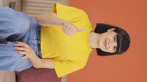 Woman Smiles Giving Thumbs Up on Couch