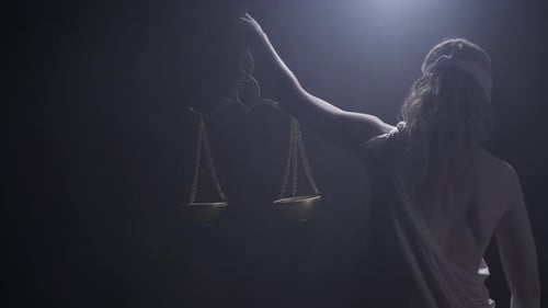 Living Statue of Themis is Holding the Statue and Looks at Them Low Lighting