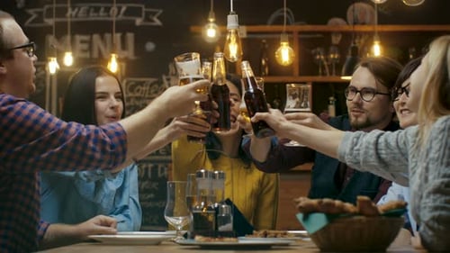 Friends Clinking Drinks Together at a Restaurant Table