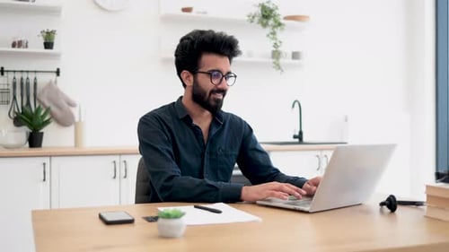 Man with Glasses Working on Laptop at Home