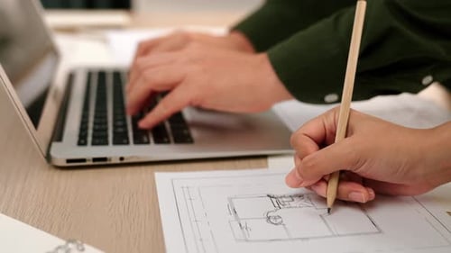 Close up of architect hand writing detail of blueprint with laptop. Delineation.