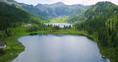 Luftbild eines Sees inmitten der Natur zwischen Bäumen und Bergen.