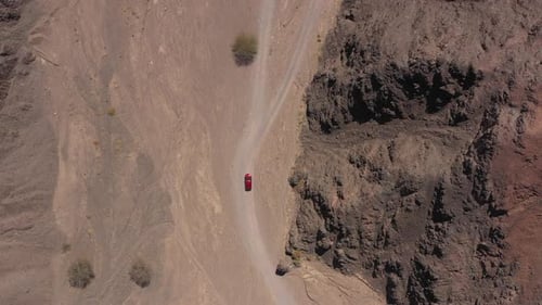 Red SUV on a desert path, high altitude aerial follow footage
