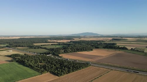 Aerial view of highway near agricultural fields with mountain in background