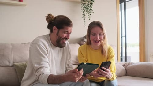 Couple Using Tablet and Smartphone on Couch