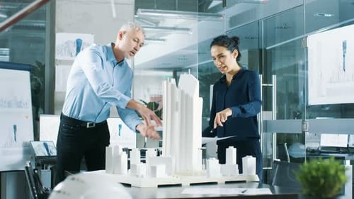 Two Professional Male and Female Architectural Engineers Work with Blueprints and on a Building Mod