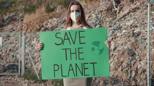 Woman Holding Save The Planet Sign in Landfill