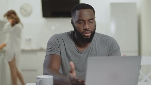 Man Video Conferencing on Laptop in Kitchen