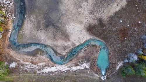 Aerial drone footage of a winding salmon stream in Michigan with turquoise water cutting through dry