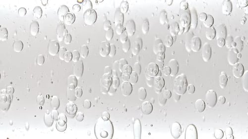 Gel fluide cosmétique transparent avec bulles de molécules et huile circulant dans un tube en verre avec liquide transparent