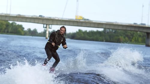 Joyful Man Wakeboarding on City River. Extreme Entertainment on Water. Athlete Moving