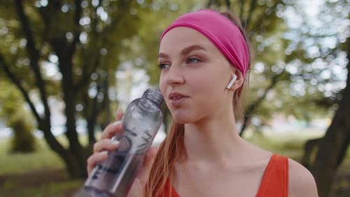 Athletic Fit Sport Jogger Young Woman Drinking Water From Bottle After Training Exercising in Park