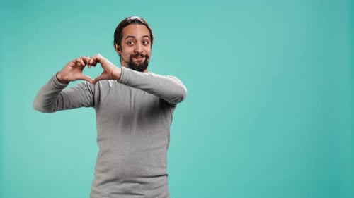 Smiling Man Makes Heart Shape with Hands