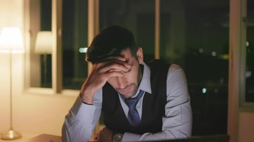 Kaukasischer Geschäftsmann arbeitet spät in der Nacht im Büro an einem Laptop